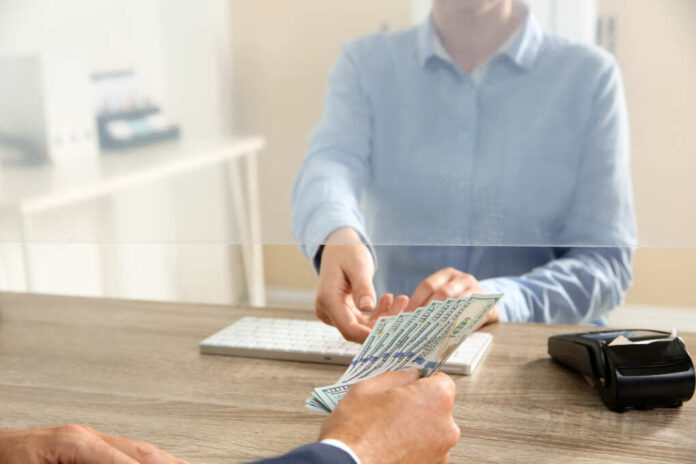 Man,Giving,Money,To,Teller,At,Cash,Department,Window,,Closeup