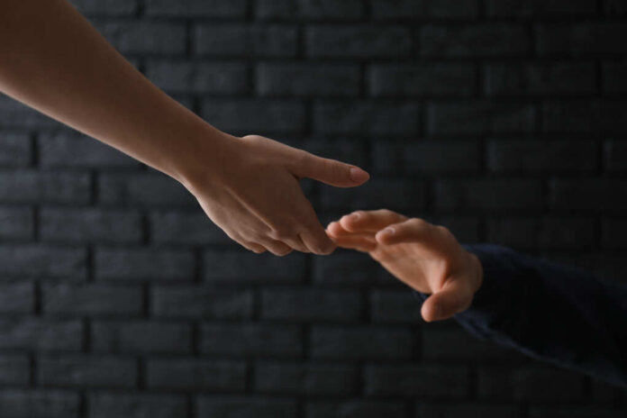 Woman,Giving,Hand,To,Depressed,Man,Against,Dark,Background.,Suicide