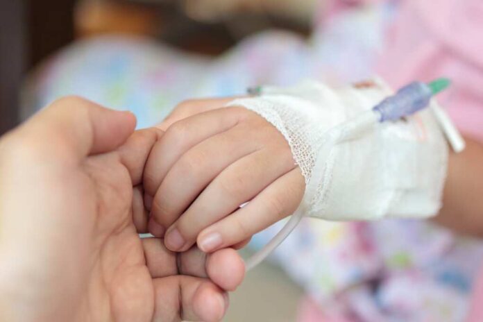 Mother,Holding,Child,Hand,With,Saline,Iv,Solution,In,Hospital