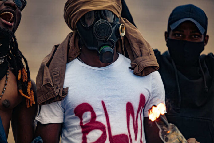 Protesters wearing masks and holding a flaming object