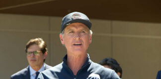 A man speaking at a press conference outdoors with a microphone