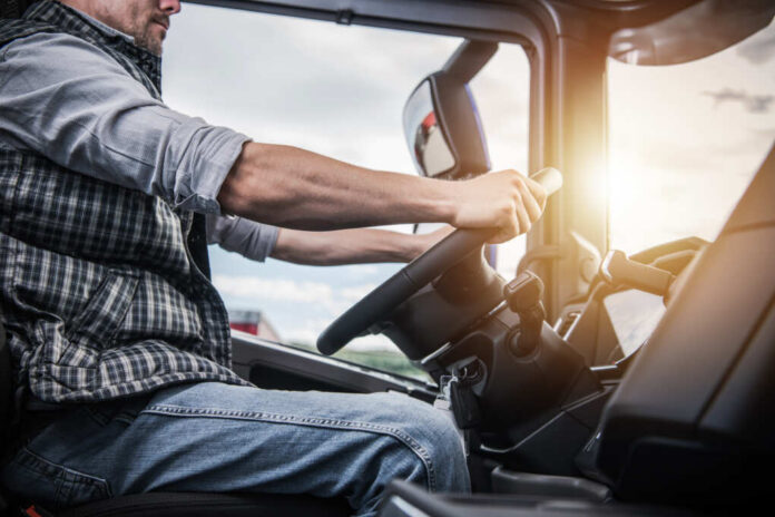 shutterstock_1209458845.jpg A truck driver gripping the steering wheel inside a vehicle cabin