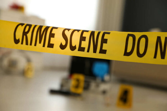 shutterstock_1925163116.jpg Yellow crime scene tape with evidence markers in a room