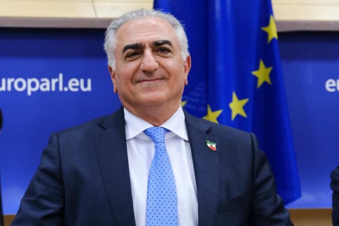 Smiling man in a suit with a blue tie, standing in front of an EU flag