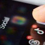 Digital Freedom in Danger: Spain’s New Tool Unveiled Close-up of a finger tapping a TikTok icon on a smartphone screen with social media labels