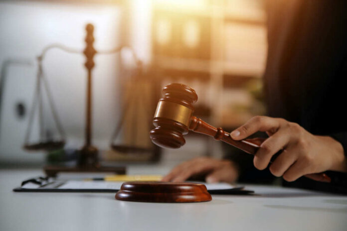 A gavel being struck on a desk in a courtroom setting