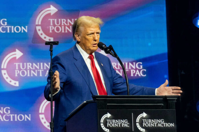 A man in a blue suit speaking at a podium with a microphone