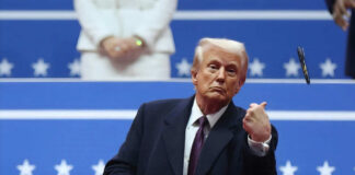 A man in formal attire gesturing during a political event