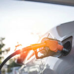 A fuel nozzle inserted into a cars gas tank during sunset