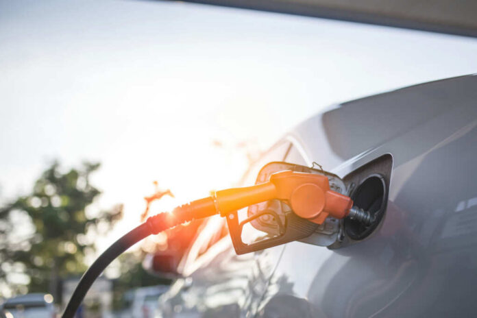 A fuel nozzle inserted into a cars gas tank during sunset