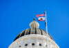 California’s Political Gamble: Losing People, Losing Power View of a state capitol dome with American and California flags against a blue sky