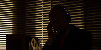 Silhouette of a man wearing headphones next to vintage audio equipment