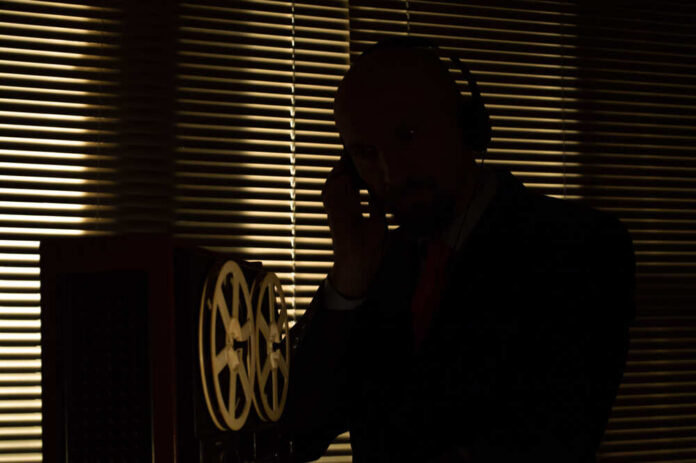 Silhouette of a man wearing headphones next to vintage audio equipment