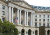 Exterior view of a government building with columns and flags