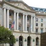 Exterior view of a government building with columns and flags