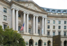 Exterior view of a government building with columns and flags