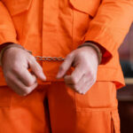 Convicted Pedophile Freed: California Fury Erupts A person in an orange jumpsuit with handcuffs