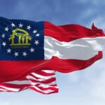 Georgia state flag and American flag waving against a blue sky