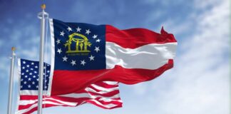 Georgia state flag and American flag waving against a blue sky