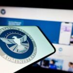 Spring Break NIGHTMARE — Democrat Standoff Cripples Airports Close-up of a mobile device displaying the TSA logo with a blurred background of a website