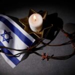 Israeli flag next to a lit candle and barbed wire