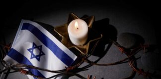 Israeli flag next to a lit candle and barbed wire