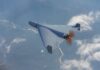 A drone flying high above the clouds with a visible propeller