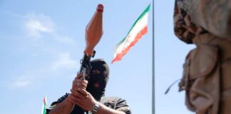 Masked individual holding a weapon during a military demonstration