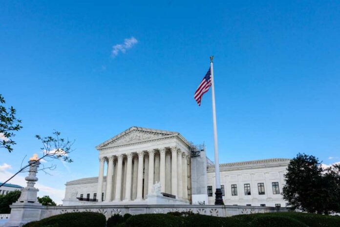 U.S. Supreme Court building with American flag and blue sky