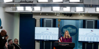 A woman speaking at a podium during a White House press briefing with journalists in attendance