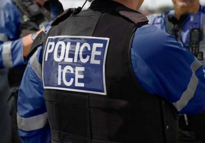 shutterstock_2615419741.jpg Close-up of a police officer's vest with 'POLICE ICE' label