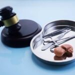 A gavel next to a surgical tray containing medical instruments and an anatomical model