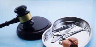 A gavel next to a surgical tray containing medical instruments and an anatomical model