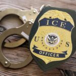 ICE’s Bold Move Amid DHS Leadership Change ICE officer badge next to handcuffs on a wooden surface