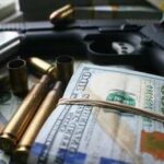 A handgun surrounded by cash and bullet casings