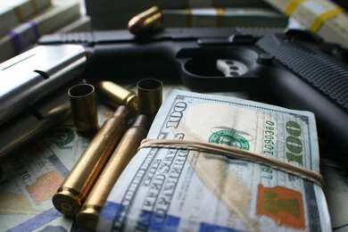 A handgun surrounded by cash and bullet casings