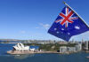 Australian flag waving in front of the Sydney Opera House and city skyline