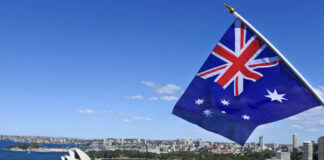 Australian flag waving in front of the Sydney Opera House and city skyline
