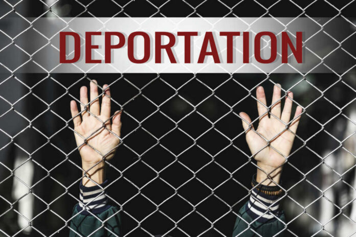Hands reaching through a metal fence with the word DEPORTATION above