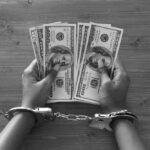 Bear Costume Scam: Unbelievable Fraud Uncovered Hands in handcuffs holding stacks of cash