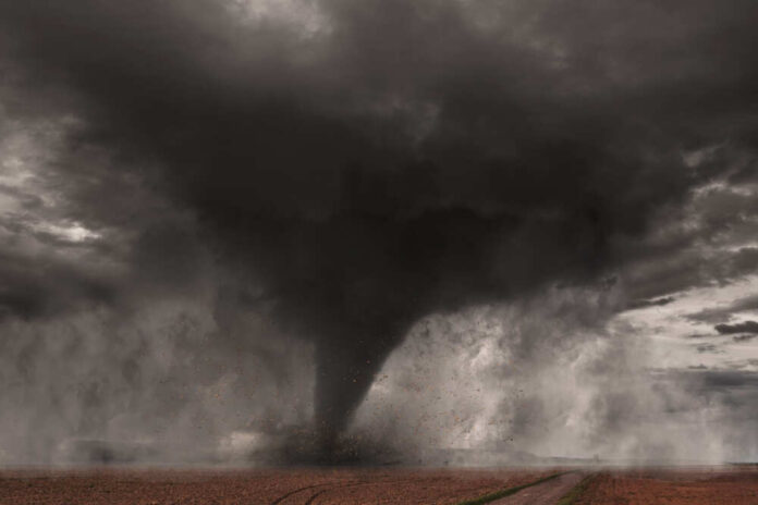 A tornado forming in a dark, stormy sky over a field