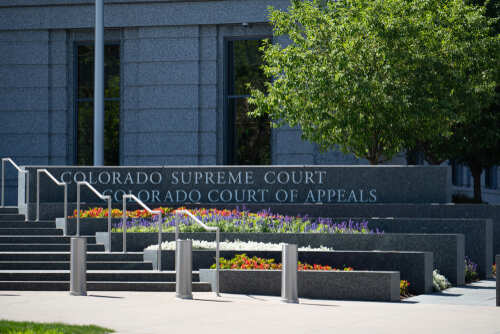 Exterior view of the Colorado Supreme Court building with landscaped flowers