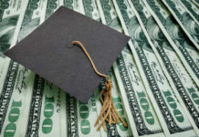 A graduation cap placed on a stack of hundred dollar bills