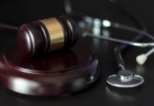 A gavel and a stethoscope on a dark surface