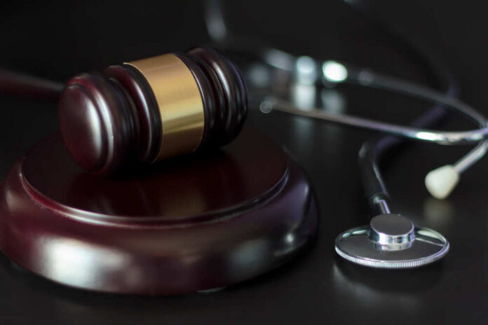 A gavel and a stethoscope on a dark surface