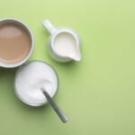 Alarming Study: Sucralose Alters DNA Across Generations! A cup of coffee, a bowl of sugar, and a creamer on a green background