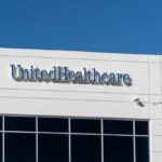 Signage of UnitedHealthcare on a modern building against a clear blue sky