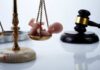 Scales of justice with a baby figurine and a gavel in the background