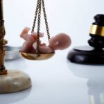 Scales of justice with a baby figurine and a gavel in the background