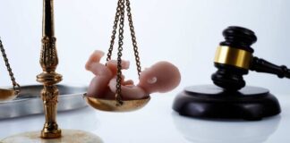 Scales of justice with a baby figurine and a gavel in the background